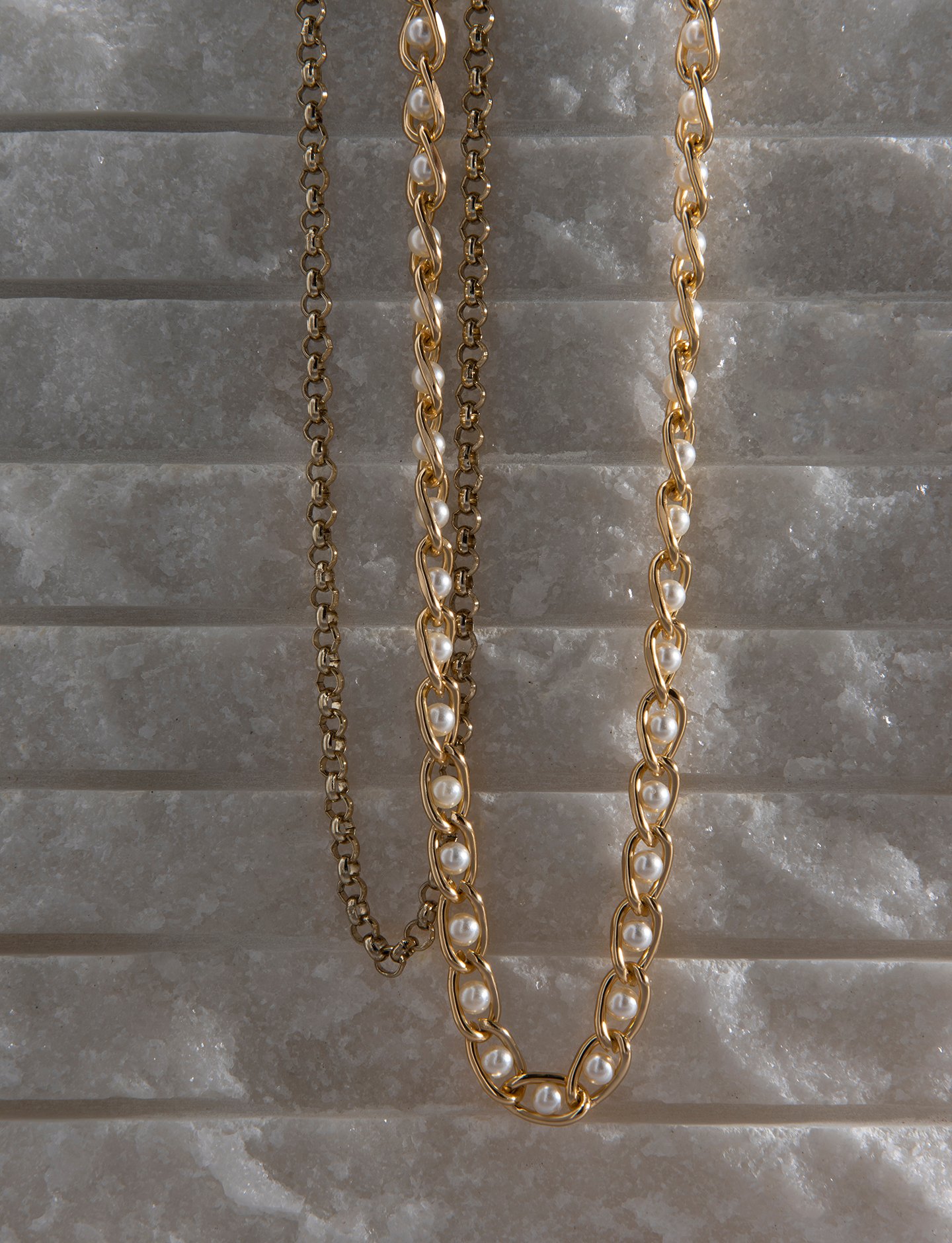 Golden Chain and Pearl Necklace on Stone Background